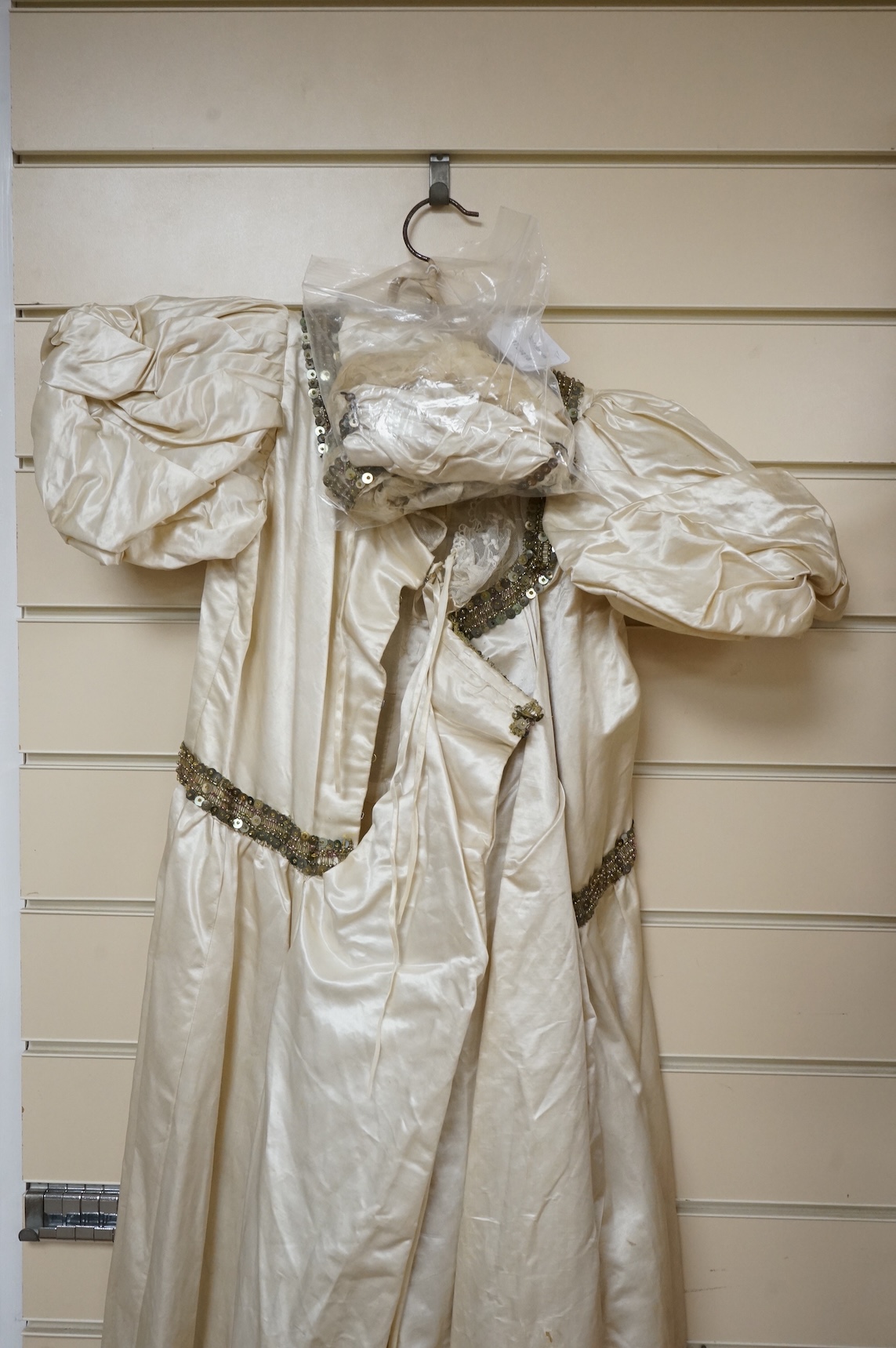 A cream silk satin theatrical costume, mounted with sequined braiding and pair of novelty shoes. Bust measurement 30inches.